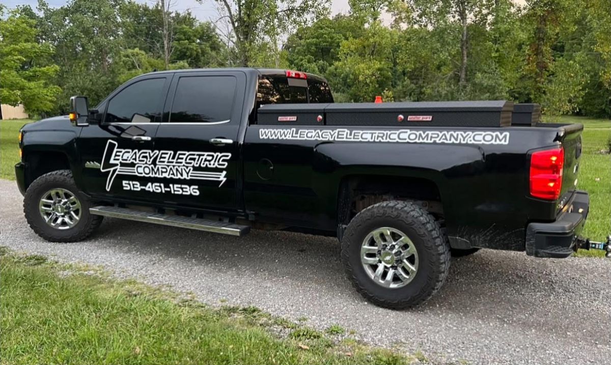 Side view of Legacy Electric Company's black work truck with a truck-bed toolbox and Legacy Electric Company lettering